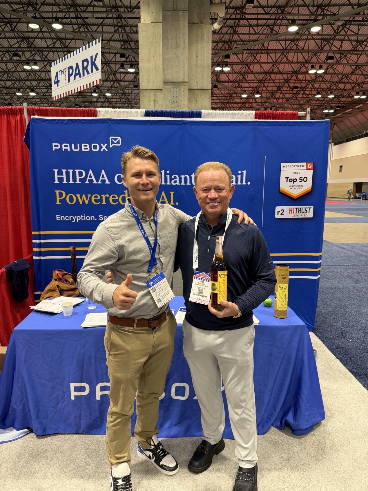 Two people smiling in front of the Paubox booth backdrop in the NCPA expo hall | NCPA Annual Convention 2026 in Kansas City