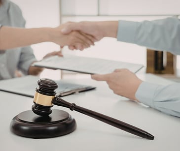 Image of two people shaking hands near a gavel. 