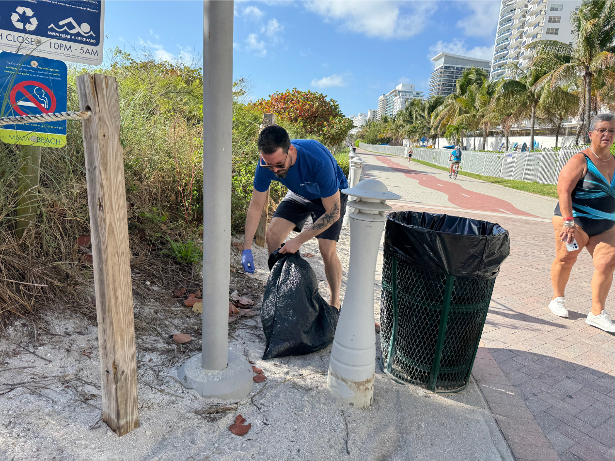 Will Ashe picking up trash near a trash can.