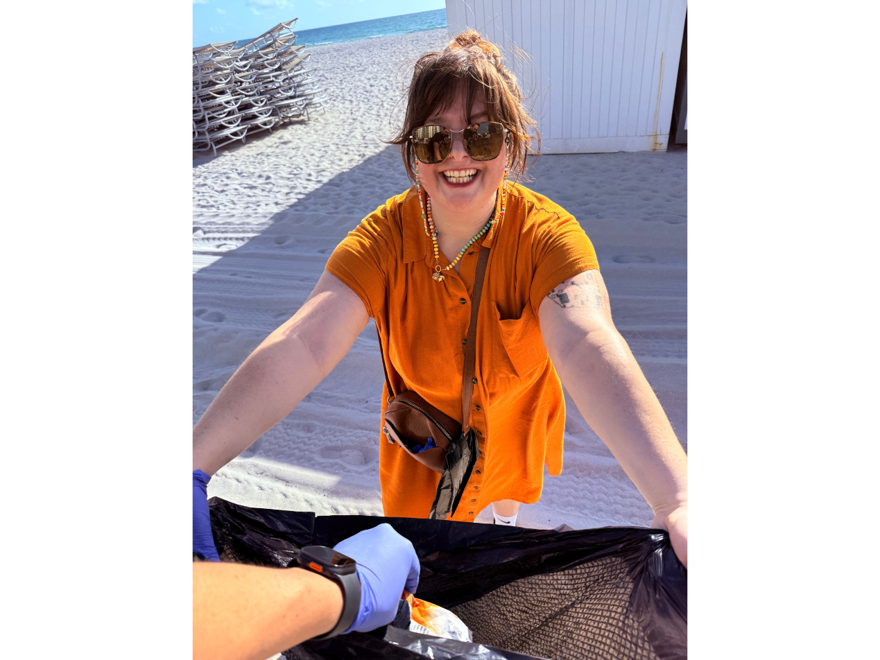 Hoala Greevy dropping off some trash he picked up into Aja Anderson's garbage bag.