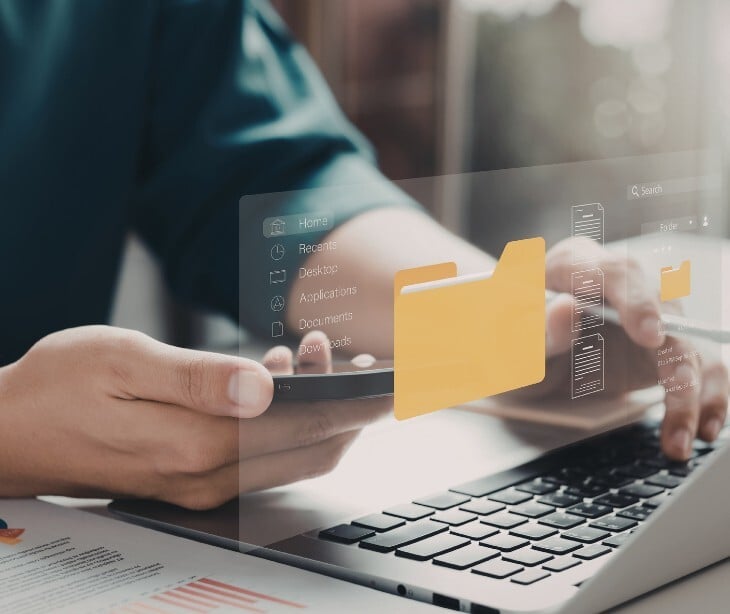 Individual on a laptop with an image of a folder floating out of the laptop. 