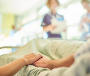 holding hands at a hospital bedside