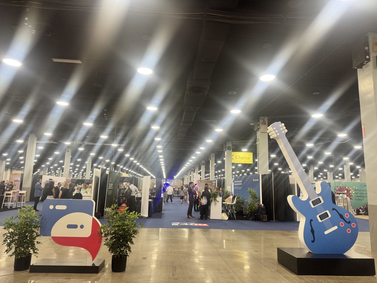 Wide view of the BHT2026 expo hall with exhibitor booths and a large guitar sculpture in the foreground | Paubox at Behavioral Health Tech 2026 in Nashville