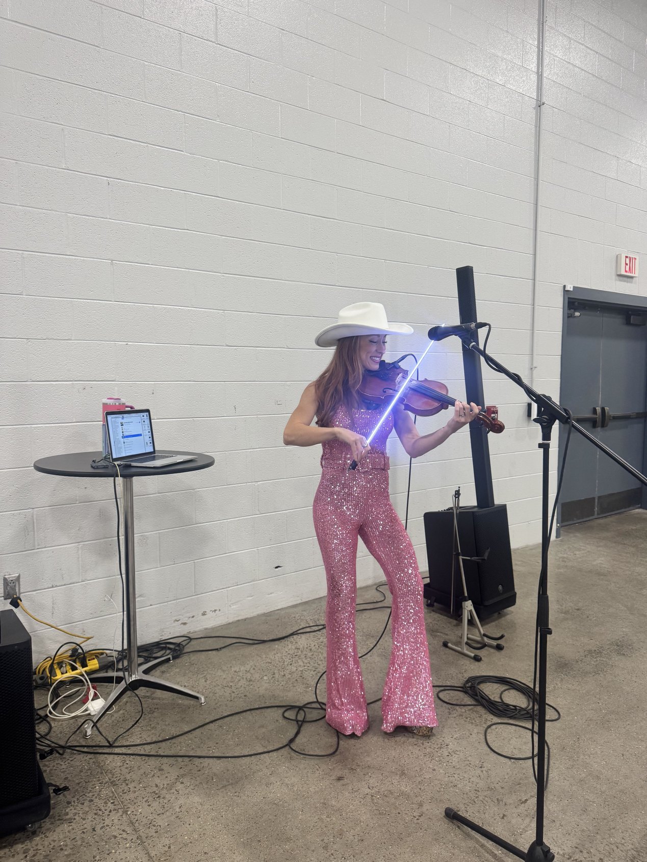 A musician in a white cowboy hat and pink sequined jumpsuit playing a light-up fiddle at BHT2026 | Paubox at Behavioral Health Tech 2026 in Nashville