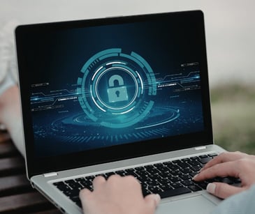 Image of someone with a laptop open. On the screen is a lock. 