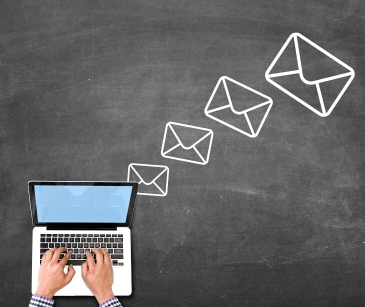 Image of someone typing on a computer with email logos near. 