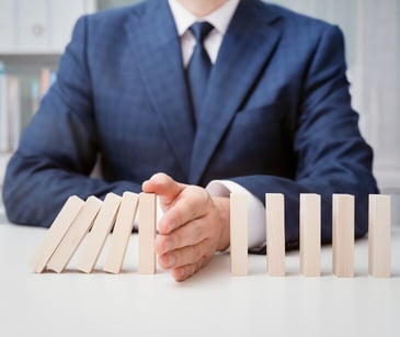 Image of someone stopping dominoes from falling over. 