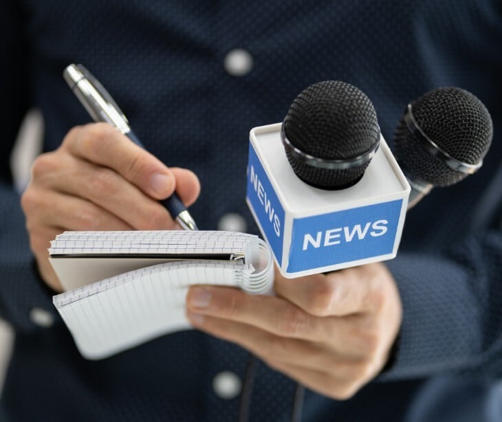 Image of a news microphone and someone taking notes. 
