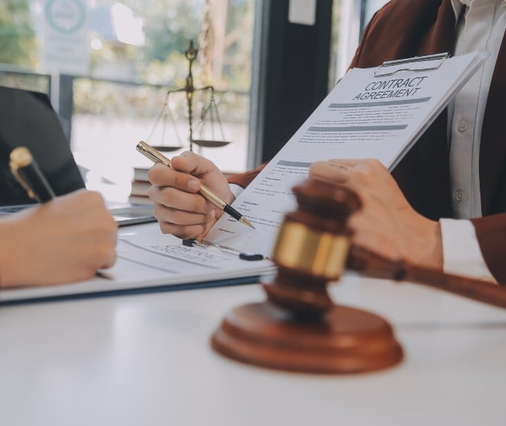 Image of someone signing a contract next to a gavel. 