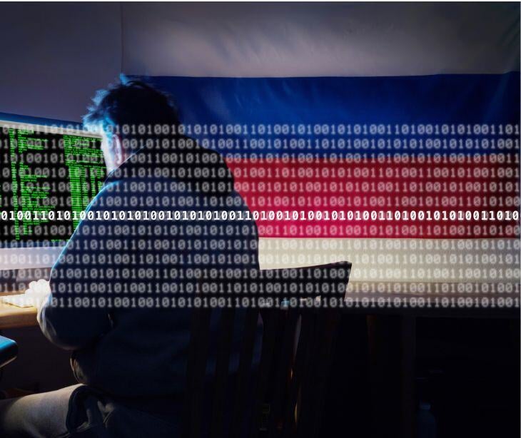 hacker at computer in front of russian flag