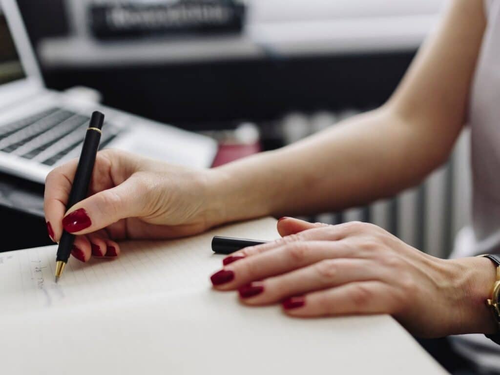 hands writing notes on desk