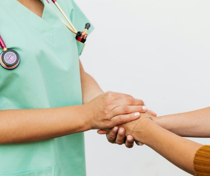 Image of a nurse holding a patient's hand.