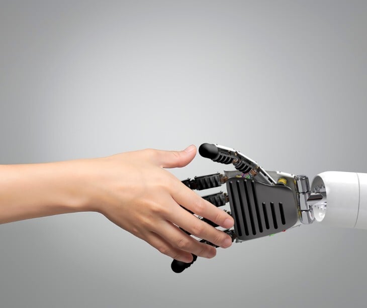 Image of a person shaking hands with a robot. 
