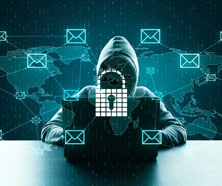 Image of a hooded figure on a laptop. 