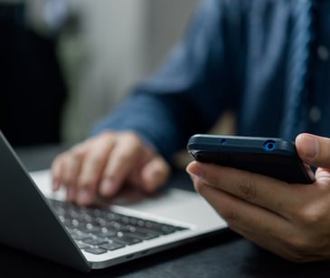 person on laptop holding cellphone