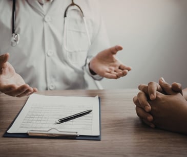Image of a patient and provider talking with a clip board on a table. 