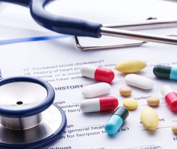 medication tablets on a paper health record with stethoscope