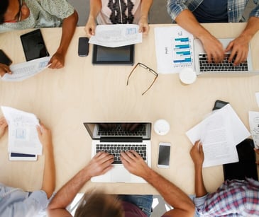 Image of individuals on a laptop at a table. 