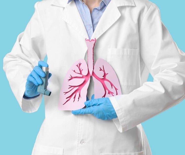 Image of a practicioner holding a cut-out of a lunch and an inhaler. 