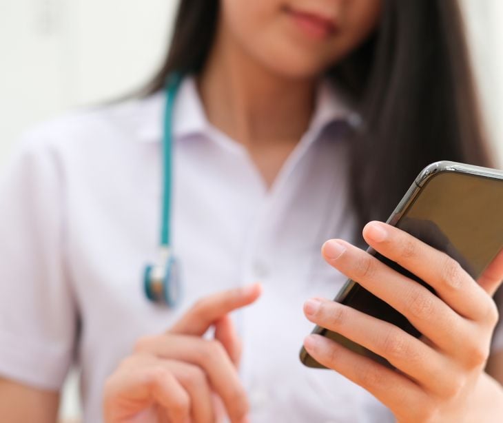 person using smartphone wearing stethoscope 