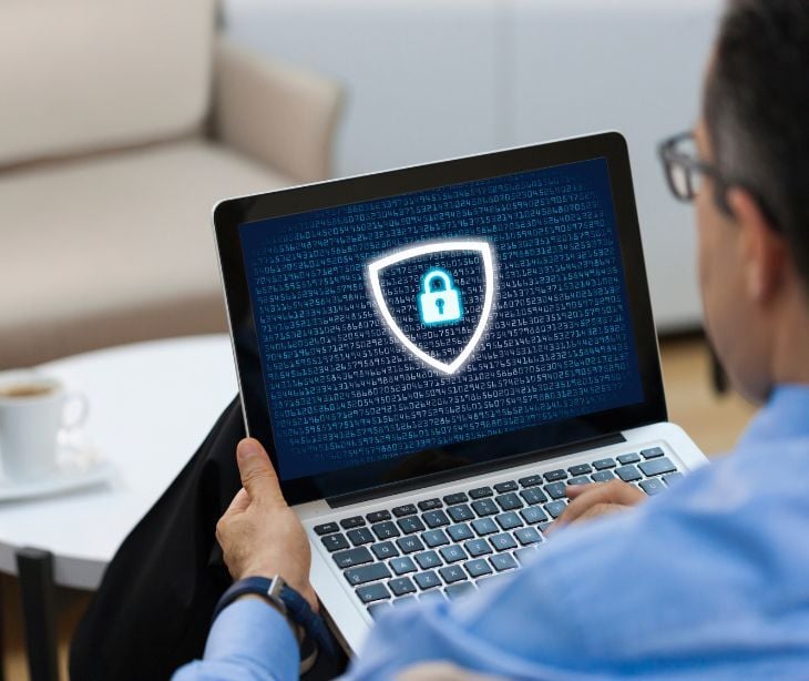 Image of someone on a laptop with a shield on it. 