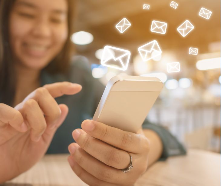 woman using smartphone with email icons floating