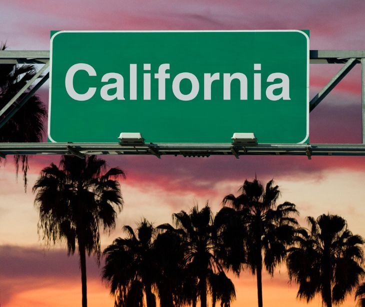 Image of a sign that reads "California" with palm trees in the background. 