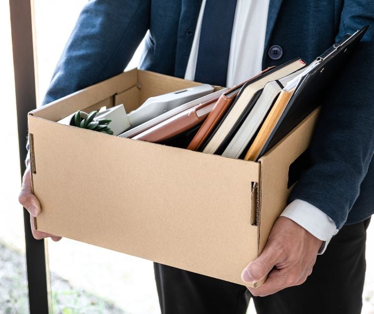person holding box of desk items