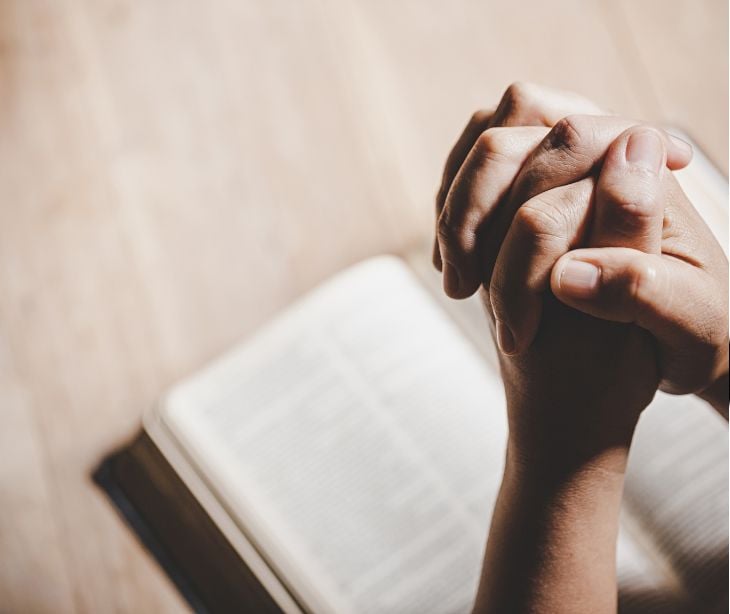 praying hands over a book