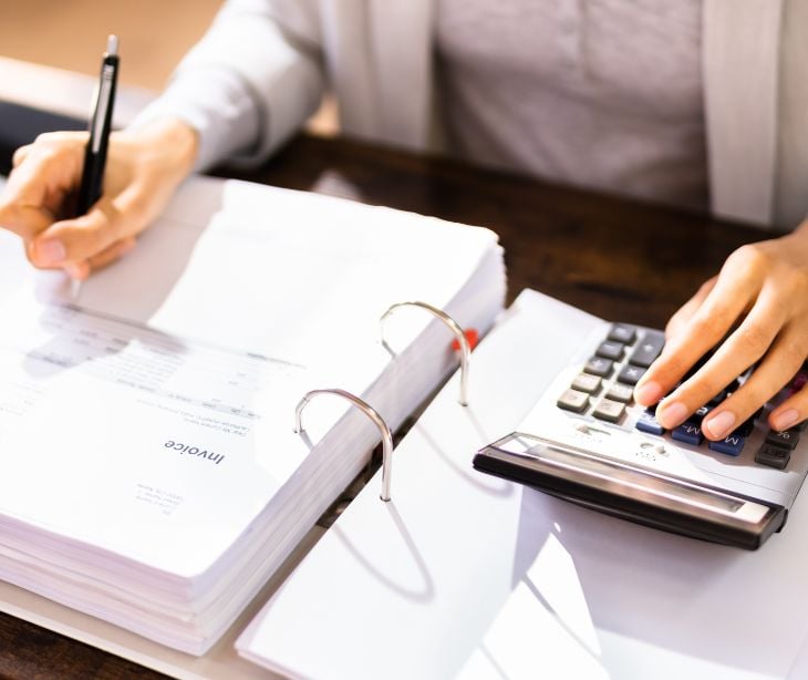 person with paperwork and calculator