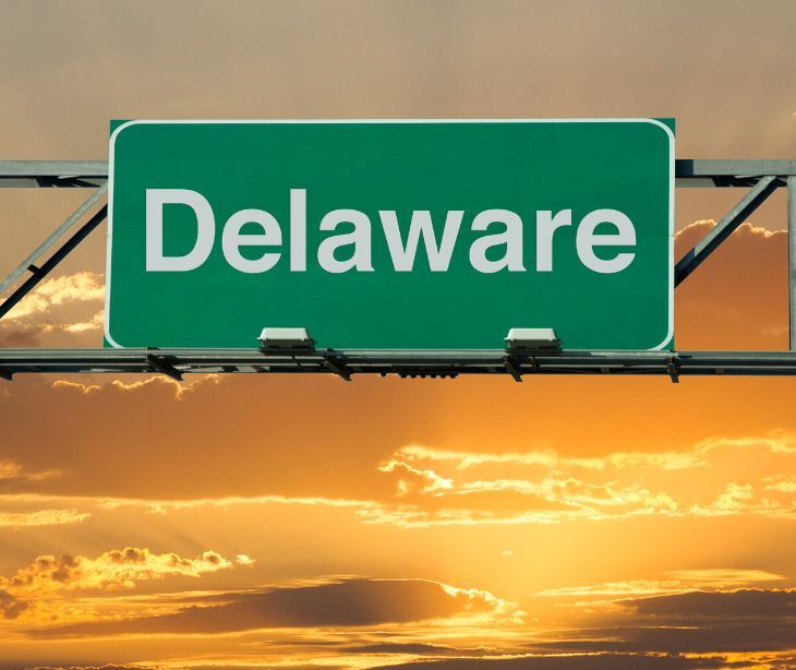 Image of a sign that says "Delaware" with a sunset in the background. 