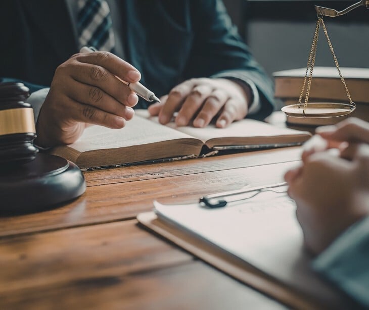 Image of two people discussing paperwork with a gavel near. 