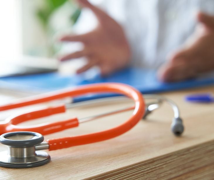 patient speaking with provider stethoscope on desk