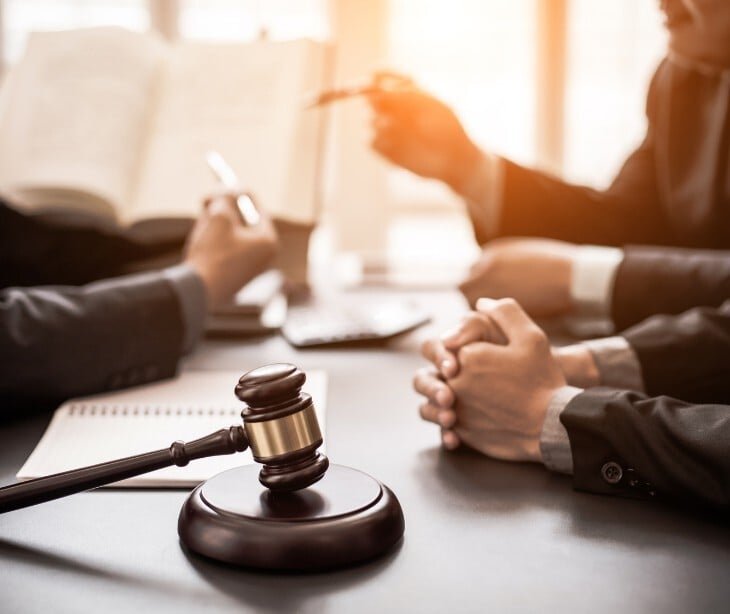 Image of several people discussing something with a gavel near them. 