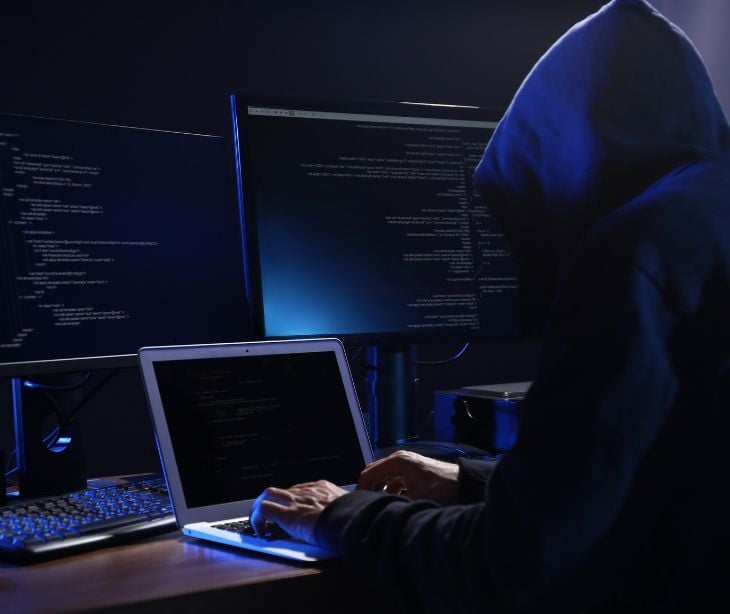 Image of a hooded figure behind a computer. 