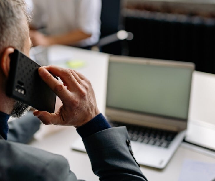 Image of someone on their phone while looking at a computer. 