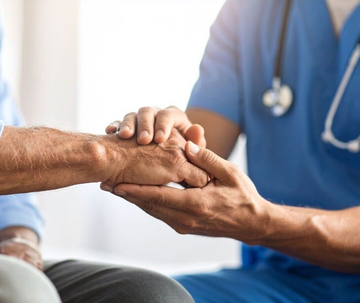 Image of a provider holding the hands of a patient. 