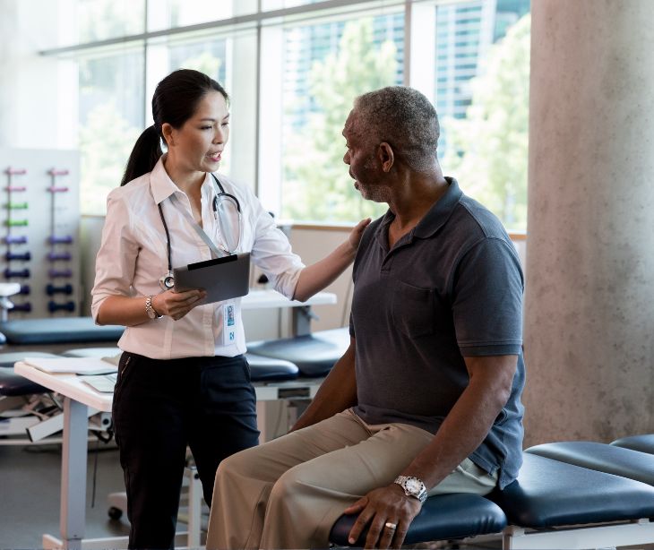 physical therapist with tablet helping patient