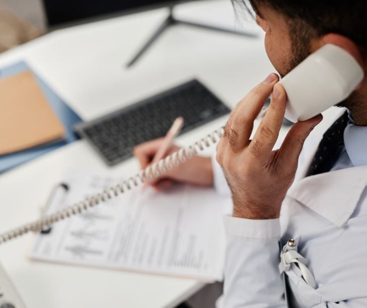 Image of someone on the phone while completing paperwork. 