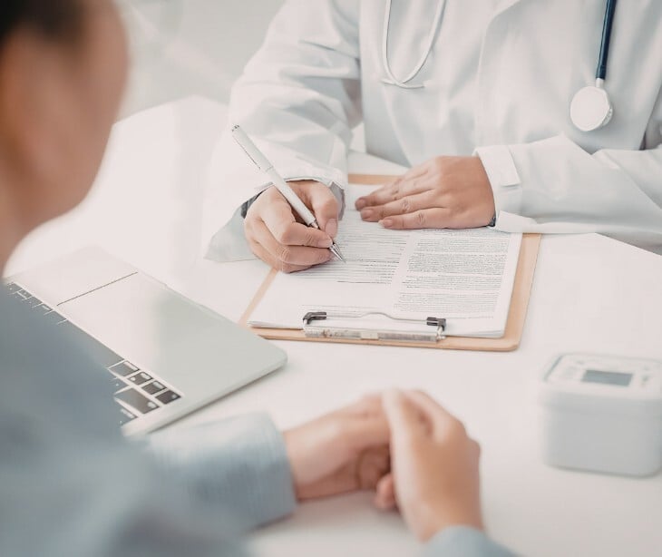 Image of a provider and patient chatting, with the provider holding paperwork. 
