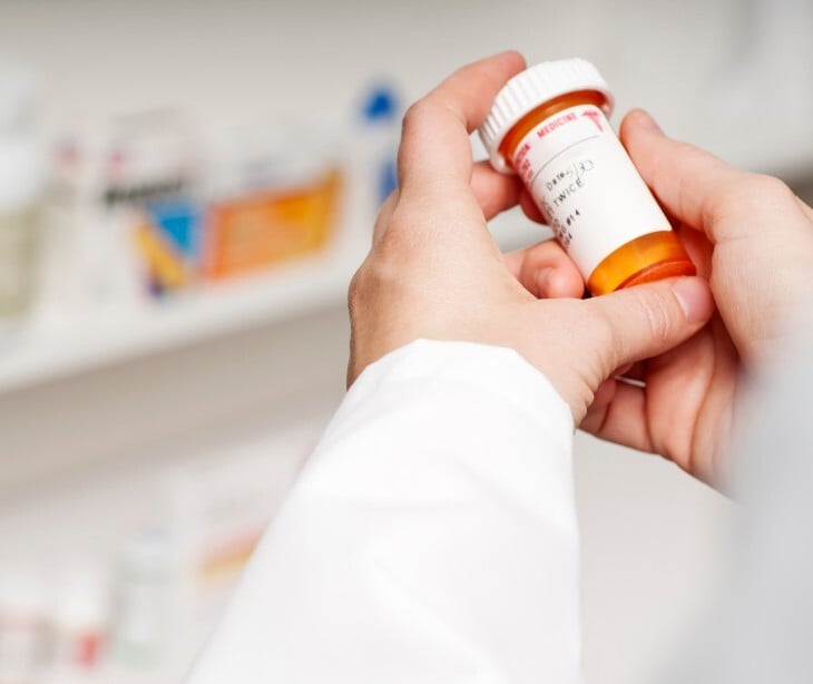 Image of a pharmacist holding a prescription bottle. 