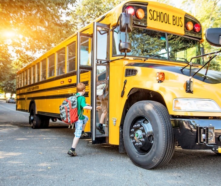 Image of a kid getting onto a school bus. 