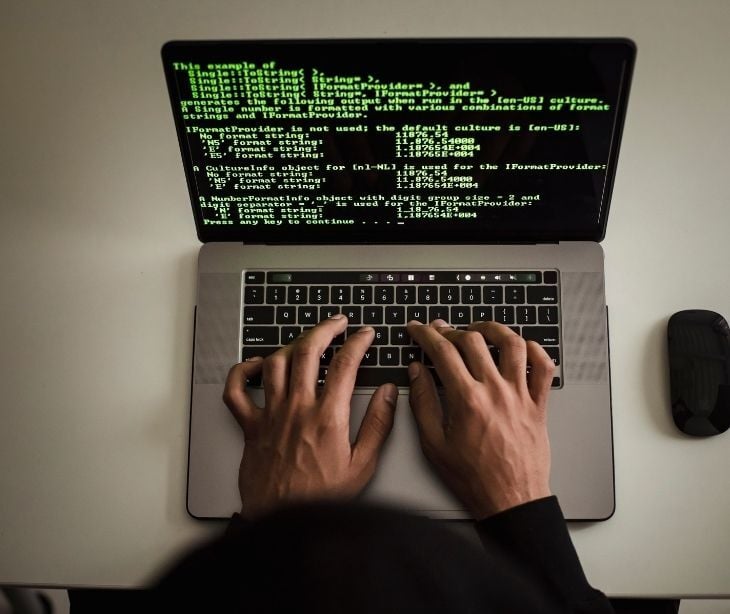 Image of someone typing green code on a computer. 