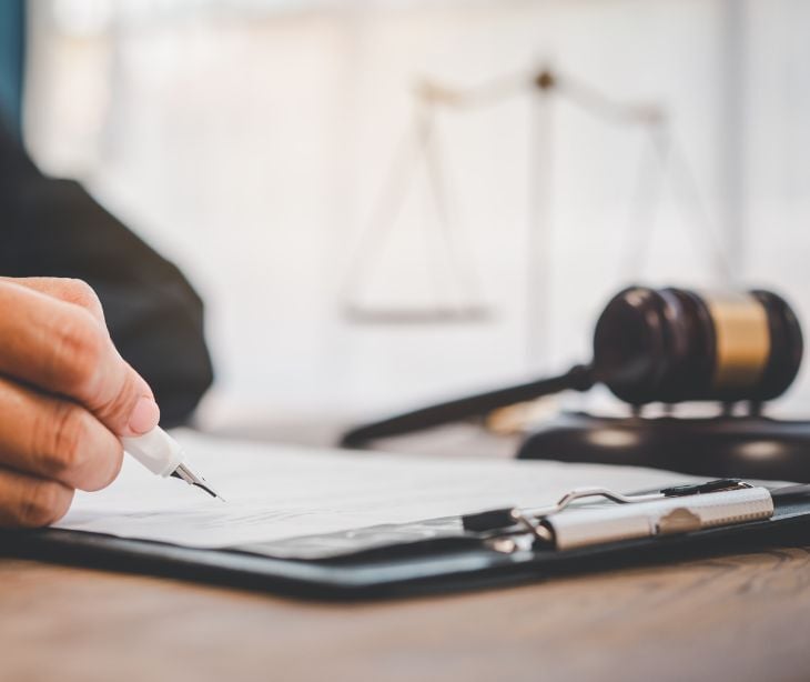 Image of someone taking notes next to a gavel. 