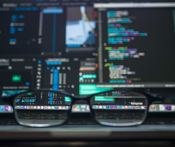 computer screen with code and glasses on desk