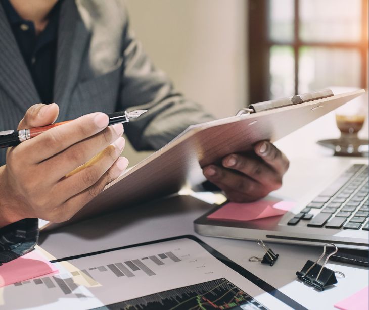 person at computer with clipboard and paperwork