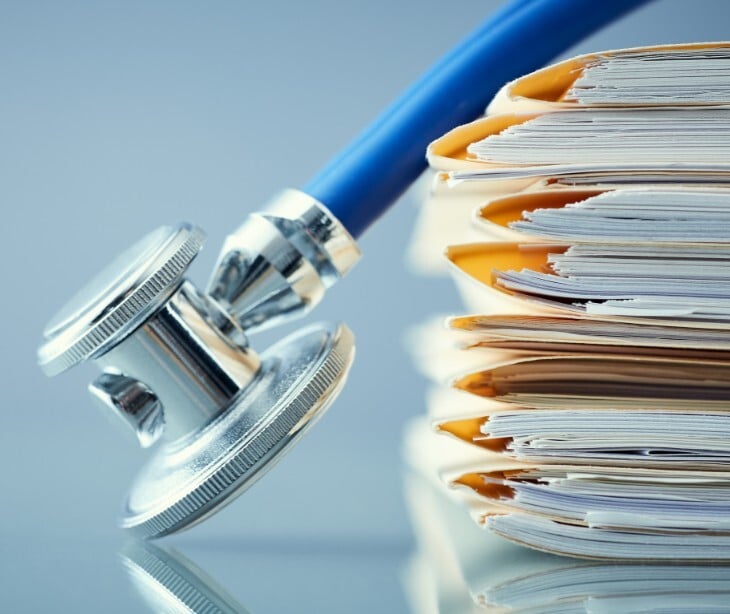 Image of a stethascope next to files with records in them. 