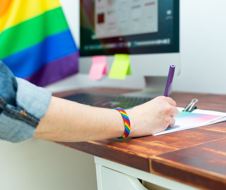 desk with laptop rainbow flack and rainbow bracelet on wrist