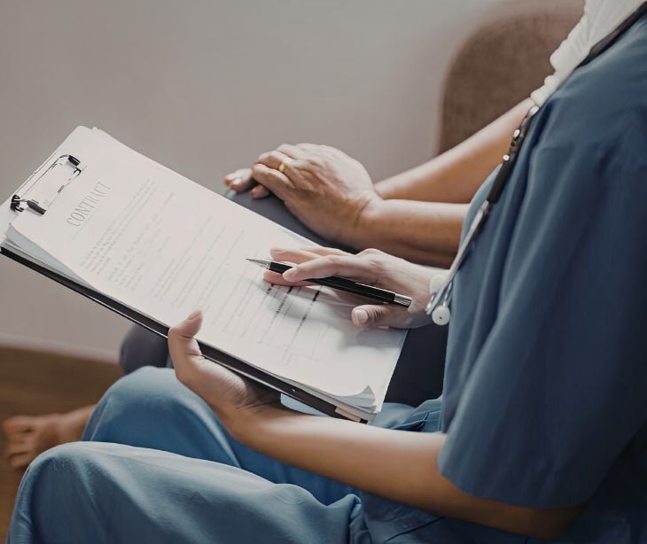 Image of a practicioner talking to another individual while holding a clipboard. 