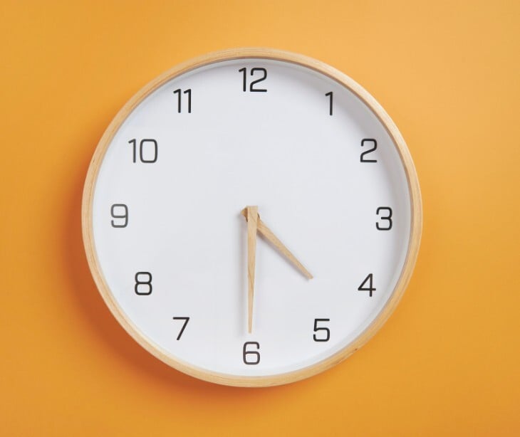 Image of a clock on a yellow wall. 